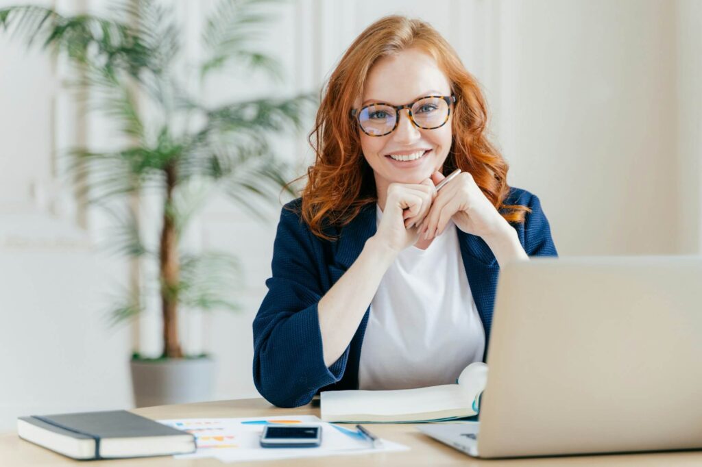pleased cheerful female economist develops financial startup project poses in office interior